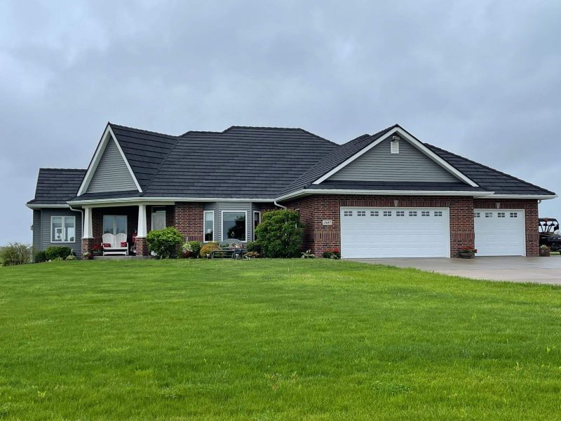 Front view of a small residential home with brand new blue-green siding installed by Stormex
