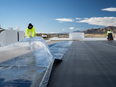 Two commercial roof installers installing Carlisle roofing products