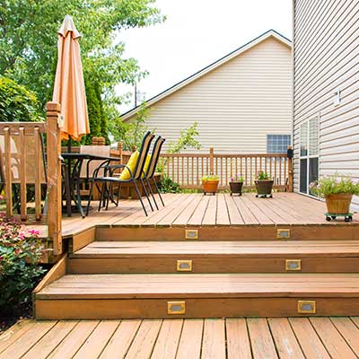 Large wooden deck with steps, pots of plants, and chairs around a table