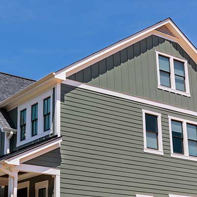 Side view of a two-story, mid-class home with green siding