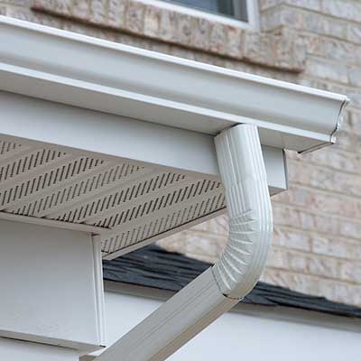 K-style white gutters with a downspout, attached to the fascia of a large home